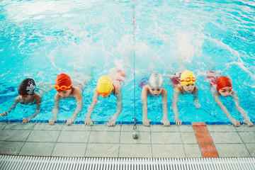 happy children kids group at swimming pool class learning to swim