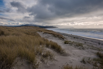Fototapeta na wymiar Sand dunes with people walking on beach, Cape Kiwanda, Oregon