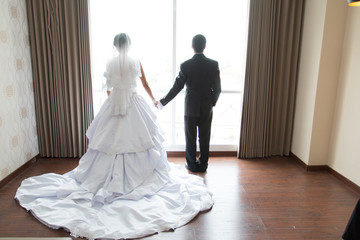 bride and groom standing at window back light in rich room tender moment