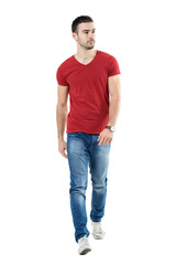 Young handsome casual man walk towards camera looking away. Full body length portrait isolated over...