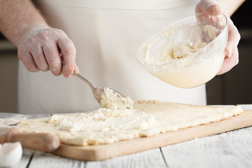 male hand picking up molten cheese from glass bowl for Cheese pie