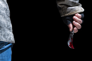 ein Mann in Lederjacke steht mit einem blutigen Messer in der Dunkelheit