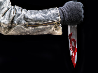 ein Mann in Lederjacke steht mit einem blutigen Messer in der Dunkelheit
