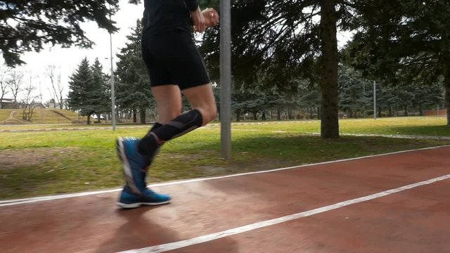 Close-up slow motion shot of a man legs jogging on the course track