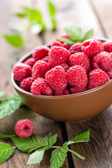 Fresh raspberry with leaves on wooden background