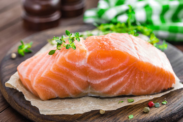 Raw salmon fish fillet on wooden board closeup