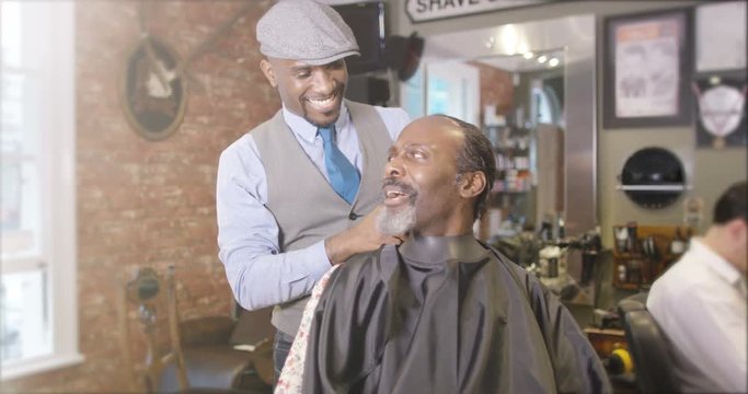 Friendly barber working on a customer in traditional retro barber shop. 