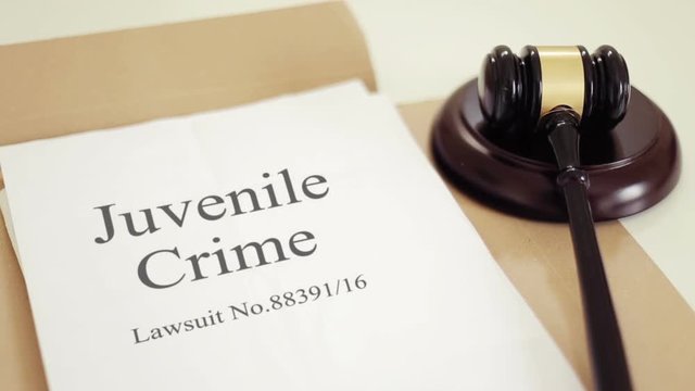 Juvenile offending lawsuit verdict folder with gavel placed on desk of judge in court