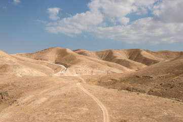 Fototapeta na wymiar Dry Judean desert with a little sandy road