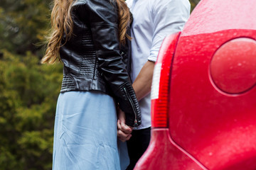 Beautiful guy with a girl hugging, stand by the car, holding hands. Love story