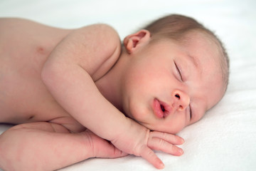 Obraz na płótnie Canvas newborn sleeps on a bed on white background, hands under my head