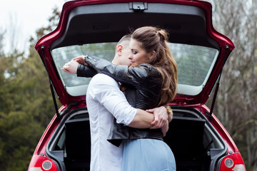 Beautiful guy with a girl hug, stand near the car, closed their eyes from the feelings that overwhelm. Love story