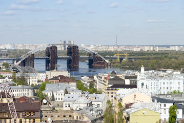 Fototapeta na wymiar View of Podil, the historic district of Kyiv, and the Podilsko-Voskresenskyi Bridge which is under construction.