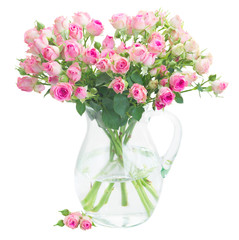 Bouquet of small pink wild roses in glass vase isolated on white background