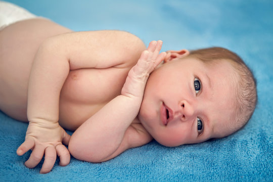 newborn baby looking at camera on bed on white background