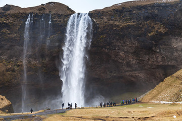 Tourists walk near Seljalandfoss waterfall