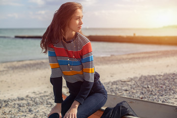 A girl sideways near a red boat on the beach by the sea