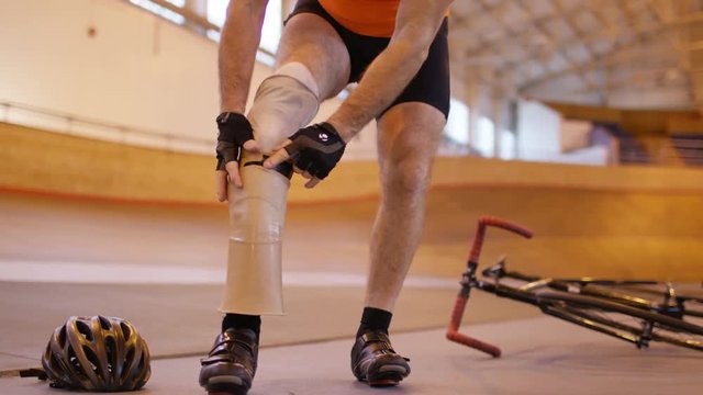  Man with prosthetic leg at cycling track attaches limb and prepares to train