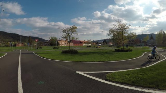 Learning driving in traffic on a traffic playground.
A little boy rides his bike on traffic playground.
