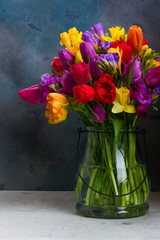 Bukiet jasnych wiosennych kwiatów w wazonie na ciemnym tle - obrazy, fototapety, plakaty