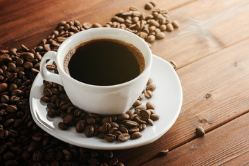 Coffee cup with saucer and beans on wooden table.