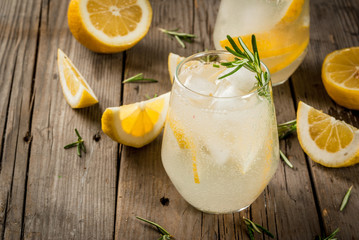 Summer refreshments. Detox water. Lemonade. Tonic with ice, lemon and rosemary, on an old wooden rustic table. Copy space