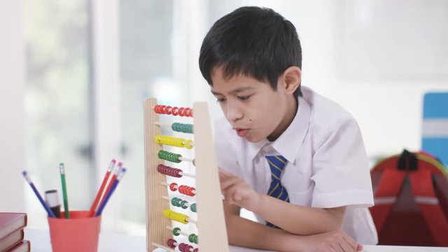  Portrait of happy little boy in classroom using an abacus