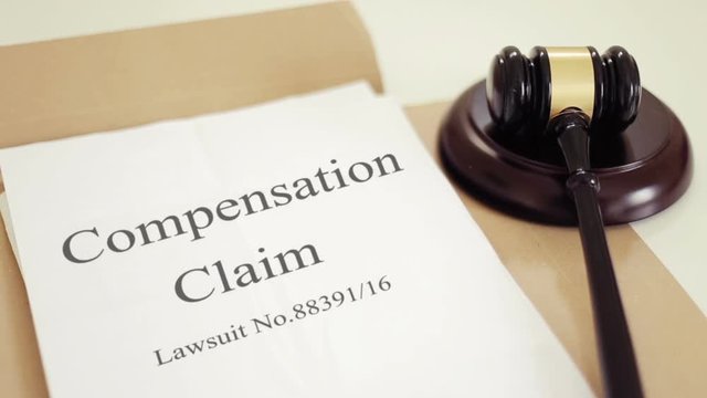 Compensation claim lawsuit documents with gavel placed on desk of judge in court