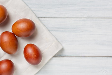 Colorful brown easter eggs on cloth and white wooden table with free space. Focus on eggs
