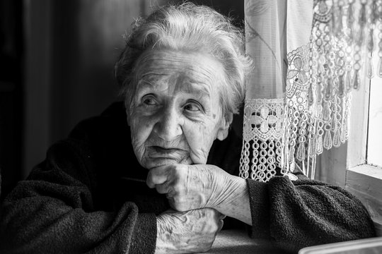 An elderly woman sitting at the table, black and white photography.
