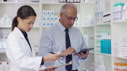  Workers in a chemist shop checking stock & discussing their work