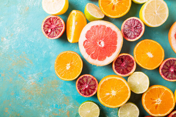 Citrus fruits on turquoise abstract background. Оrange, lemon, grapefruit, mandarin, lime. Mixed festive colorful tropical and citrus fruit sliced. Healthy eating photo concept. Copyspace - obrazy, fototapety, plakaty