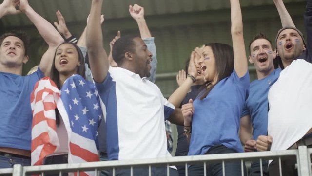  Excited fans with US flag in sports crowd, celebrating & cheering on team