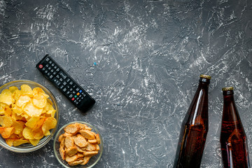 Fototapeta na wymiar TV control, snacks, beer on dark background top view space for text