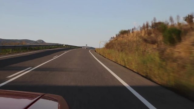 Traveling Frontal desde Coche por carretera, subiendo una cuesta en curva, hasta descubrir en la otra vertiente chimeneas de una Central de Produccion electrica mediante carbon