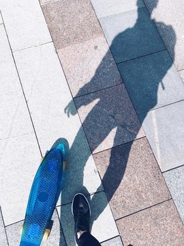 Hipster men on skateboard with blue boadr, shadow on a road, sunny day outdoor