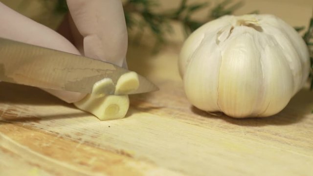 Slicing garlic on wooden tray in slow motion