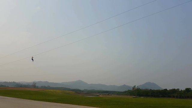 man flying down with zip line in Chiang Rai, Thailand. Silhouette.