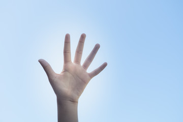 Closeup hand in the air against a clear sunny blue sky in a conceptual image with copy space
