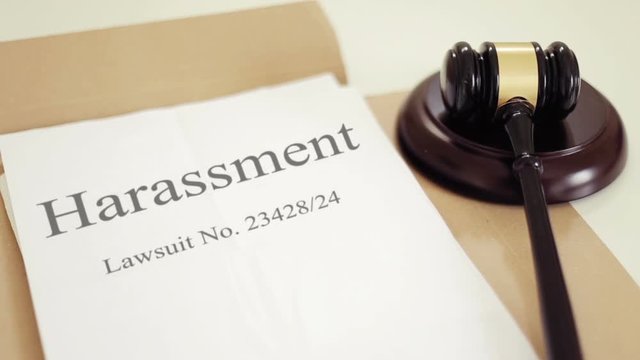 Harassment lawsuit verdict folder with gavel placed on desk of judge in court