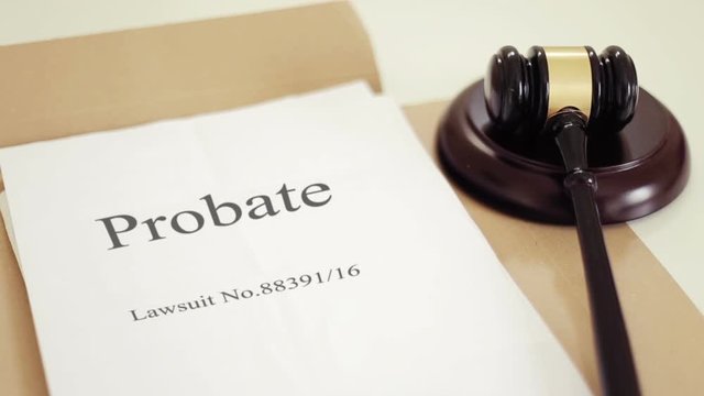Probate lawsuit documents folder with gavel placed on desk of judge in court