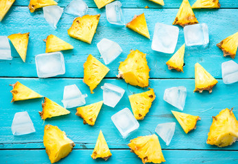 the summer pineapple is slice for eat with cold ice on blue wooden background.