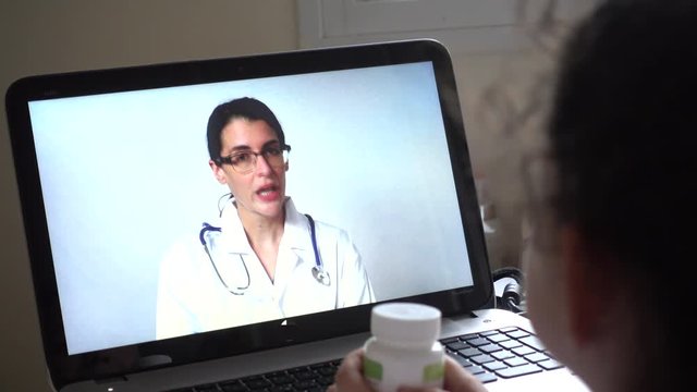 Doctor speaks to patient using telemedicine service on laptop