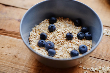 Oat flakes with blueberry in a blue cup on a wooden table.