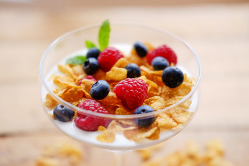 Crunchy corn flakes with some wild berries in a glass cup.