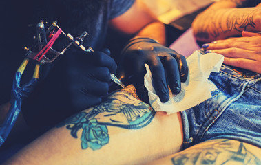 Close up image of making a tattoo on a woman's leg.