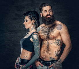 Fototapeta na wymiar Portrait of shirtless, tattooed bearded male and brunette female with tattoo ink on her torso.