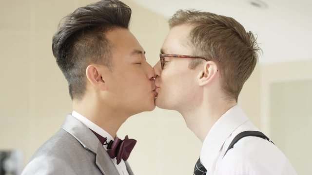  Young gay couple getting ready for wedding kiss & make heart shape with hands