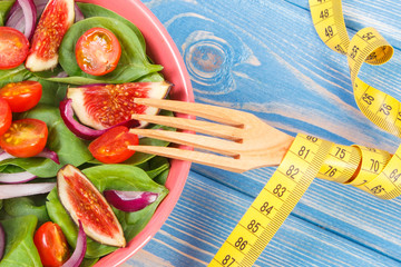 Fresh fruit and vegetable salad, fork with tape measure, healthy lifestyle, slimming and nutrition...