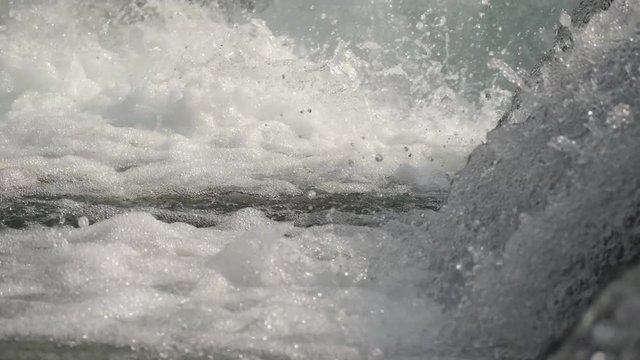 Slow motion water floating down a cascade of a river, close, in 4K